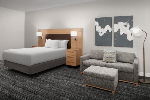 夏延夏延西南/市中心地区万豪广场套房酒店的一间卧室配有一张床、一张沙发和一把椅子