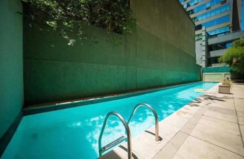 圣地亚哥Luminosa habitacion con baño privado en el centro de Providencia的蓝色的游泳池,设有绿色的墙壁和楼梯