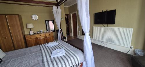 布莱克浦The Holmlea的一间卧室配有带窗帘的床和电视。
