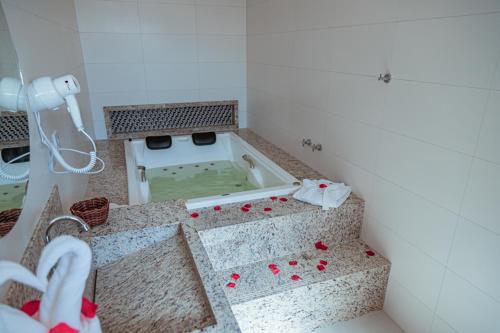 塞古罗港Orquídeas Praia Hotel的浴室配有浴缸,地板上设有红色玫瑰花