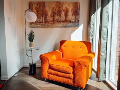 格林斯伯勒Cozy Guest House Studio Apartment的一张橙色椅子,放在带桌子的房间