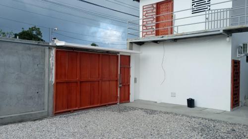 萨利纳斯HOSTAL SALINAS HOUSE的房屋一侧的车库,有红色的门