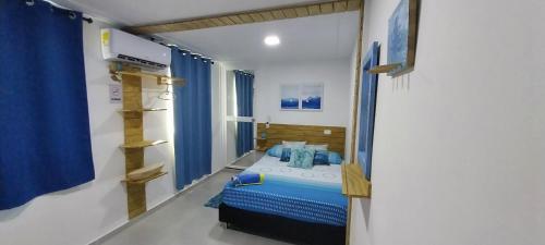 普罗维登西亚POSADA ALEENY的一间设有床铺的卧室,位于带蓝色窗帘的房间