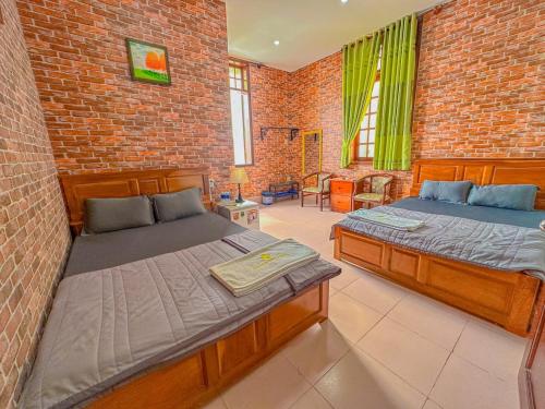 芹苴Hoàng Sơn's Home的一间卧室设有两张床和砖墙