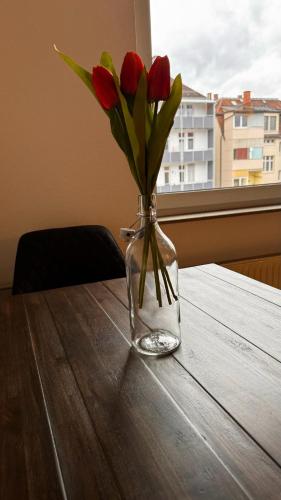 斯图加特Apartment 1 im Lehenviertel的一张桌子上装有红玫瑰的花瓶