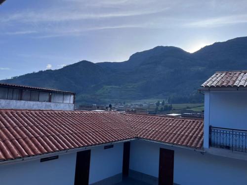 Chavín de HuantarHotel Restaurante Minas Cocha的从两栋建筑的屋顶上可欣赏到山脉美景