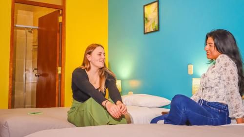 库斯科Wild Rover Cusco的两名妇女坐在房间里的床上