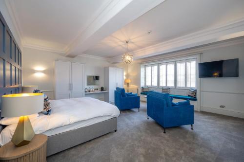 亨斯坦顿The Golden Lion Hotel的一间卧室配有一张床和两张蓝色椅子