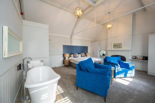 亨斯坦顿The Golden Lion Hotel的一间卧室配有一张床、蓝色的椅子和一个浴缸