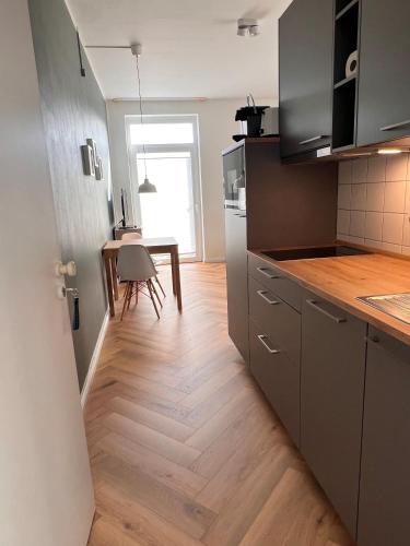 吕根岛上的维克Heimathafen Wiek的厨房铺有木地板,配有桌子。