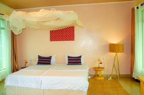 RuhengeriKarisimbi Cave Resort的一间卧室配有一张带天蓬的白色床