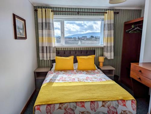 班多伦Fairy Bridge Lodge的一间卧室配有一张带黄色枕头的床和一扇窗户