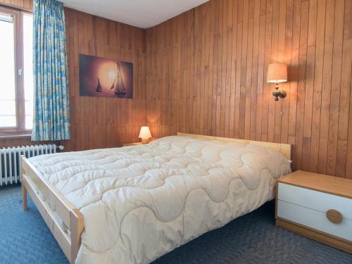 蒂涅Appartement Tignes, 2 pièces, 5 personnes - FR-1-449-167的一间卧室设有一张大床和木墙