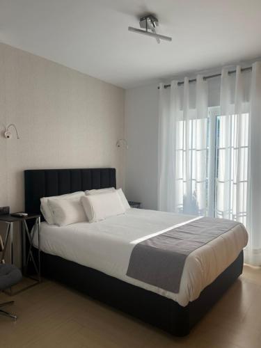内尔哈Plaza de España Boutique Apartment的一间卧室设有一张大床和两个窗户。