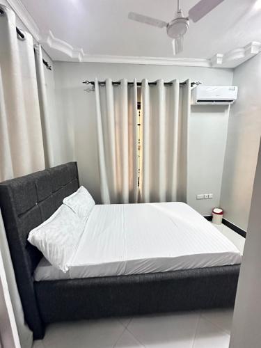达累斯萨拉姆Rejao Homes的一间卧室配有一张带白色床单和窗帘的床