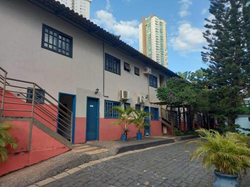 戈亚尼亚Hotel Serras De Goyaz Bueno, Goiânia的白色的建筑,在街上有蓝色和红色的门