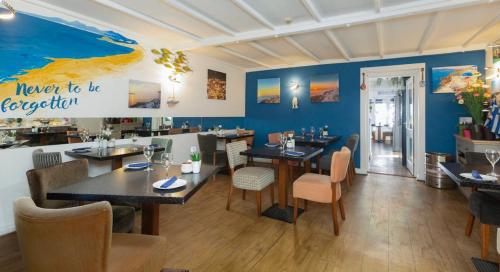 圣赫利尔泽西得勒唐旅馆的餐厅设有桌椅和蓝色的墙壁