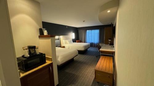 金斯顿金士顿万豪万怡酒店的酒店客房设有一间带两张床和一张书桌的卧室