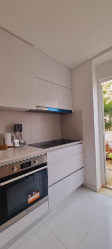波尔图Owls Hostel Ribeiro的厨房配有白色橱柜和炉灶。