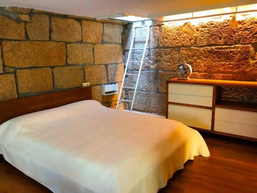 马林Casa Boutique Marín 1910的一间卧室设有一张床和石墙