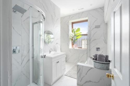 蒙特利尔Le Nomade MTL的带淋浴和盥洗盆的白色浴室
