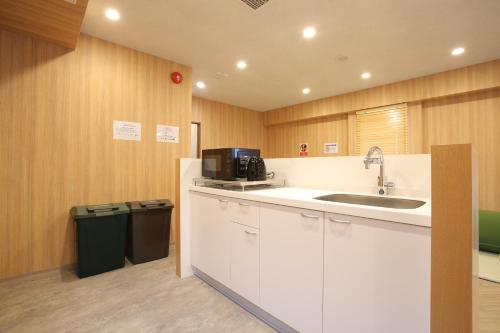 东京OHWA hostel minowa station的厨房配有水槽和带微波炉的台面。