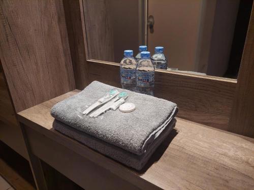 万隆Emerald Apartel的浴室柜台提供2瓶水和毛巾