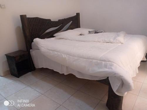 基加利Remera的一张带白色床单和枕头的床