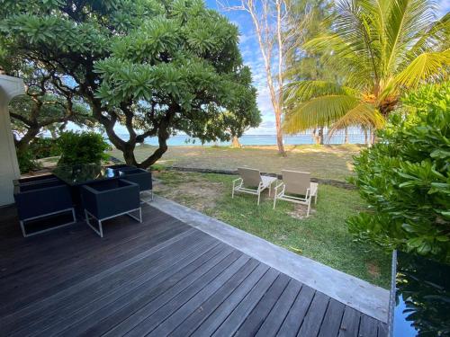 贝尔马尔Villa No2 - Sun Tan Palmar的海滩上带椅子和桌子的木制甲板