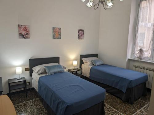 热那亚CasaLeonardo的一间卧室配有两张床、两盏灯和吊灯。