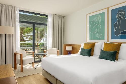 加瓦AC Hotel Gava Mar的卧室配有一张白色大床和一张桌子及椅子