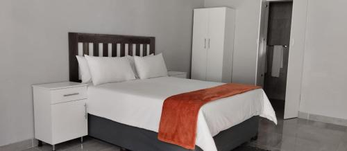 德班Abay Lodge的卧室配有白色的床和木制床头板