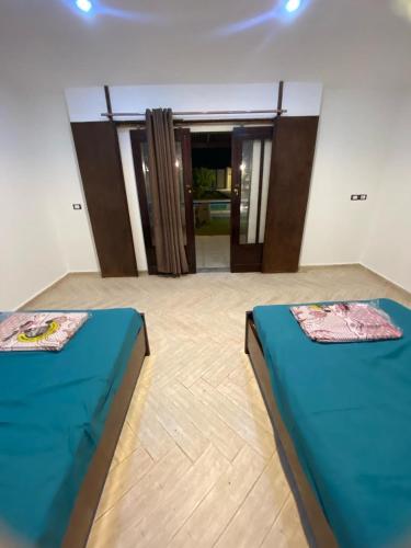 Qaryat ash Shamālīشاليه للايجار اليومي بالريف الاوروبي的配有门的房间的两张床