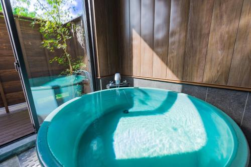 由布市The Village Yufuin Onsen Glamping的带窗户的浴室内的蓝色浴缸