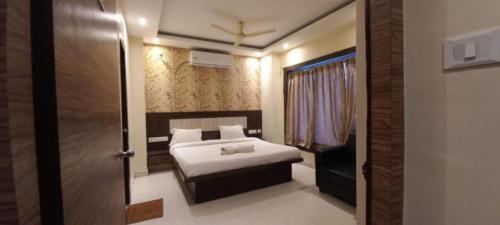 普里Hotel Home Town Puri - Lift - Parking - Near Golden Beach - Excellent Service Recommended的一间卧室配有一张床,一扇门通往一个房间