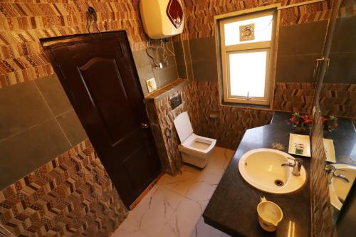 古尔冈Vagmi Inn的一间带水槽和卫生间的浴室以及窗户。
