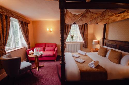 坎特伯雷豪菲尔德庄园酒店的一间卧室配有天蓬床和红色沙发