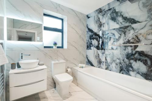寇斯顿Cozy Two Bedrooms Flat in Coulsdon, CR5的浴室配有白色浴缸、卫生间和水槽。