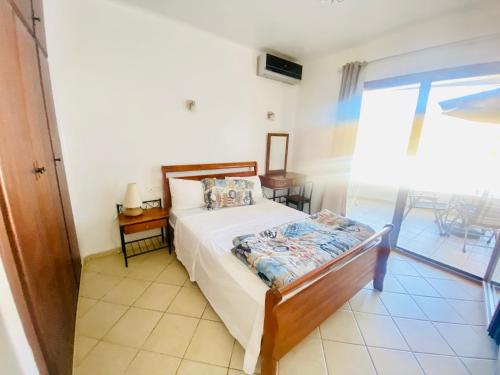 卡博尼格洛Cabo Dream Apparthotel的一间卧室配有一张床、一张桌子和一个窗户。