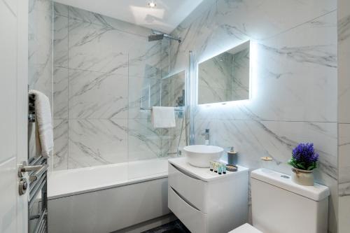 寇斯顿Modern Comfort Two Bedrooms Flat, Coulsdon CR5的白色的浴室设有浴缸、卫生间和水槽。