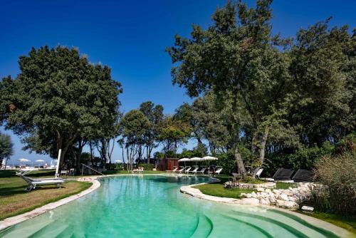 安科纳福缇诺那波里昂义科酒店的公园里的一个游泳池,有树和椅子