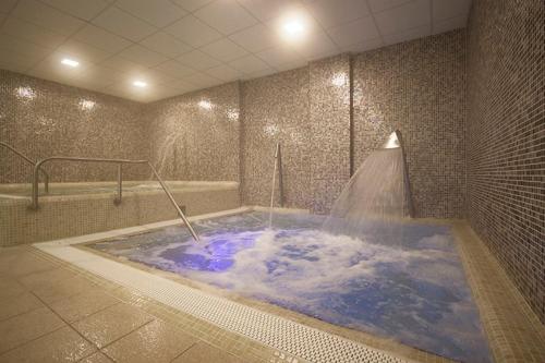 埃格尔森特伊什特万酒店的按摩浴缸,配有蓝色水淋浴