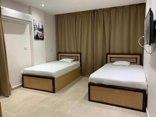 赫尔格达شاليه داخل ميراج اكوا بارك的配有电视的酒店客房内的两张床