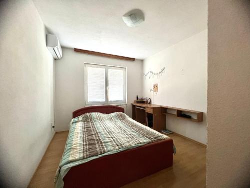 IlijašApartment with Garden的一间卧室配有一张床、一张书桌和一个窗户。