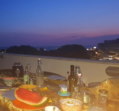 蒂勒尼亚Attico Vista Mare的阳台上的桌子上摆放着食物和瓶子