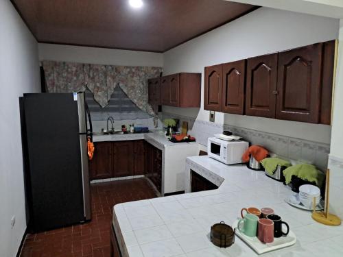 利比里亚Hostel Casa Mar的厨房配有木制橱柜和黑色冰箱。