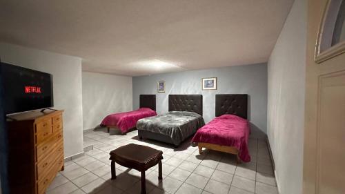Hotel y Cabañas Cascada de Basaseachi的配有两张粉红色床单和电视的客房