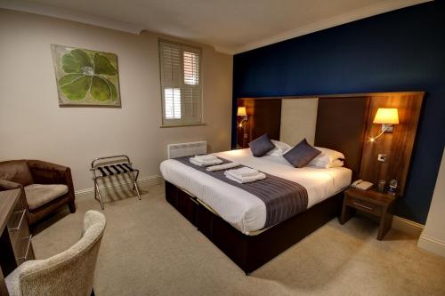 滨海绍森德罗奇福德酒店的一间卧室配有一张大床和一把椅子