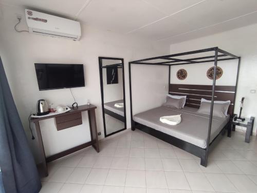 PoponguineLa residence latinaya的一间卧室配有一张天蓬床和一台电视机