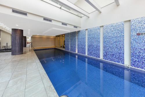 阿德莱德Oaks Glenelg Liberty Suites的墙壁上设有蓝色瓷砖的游泳池